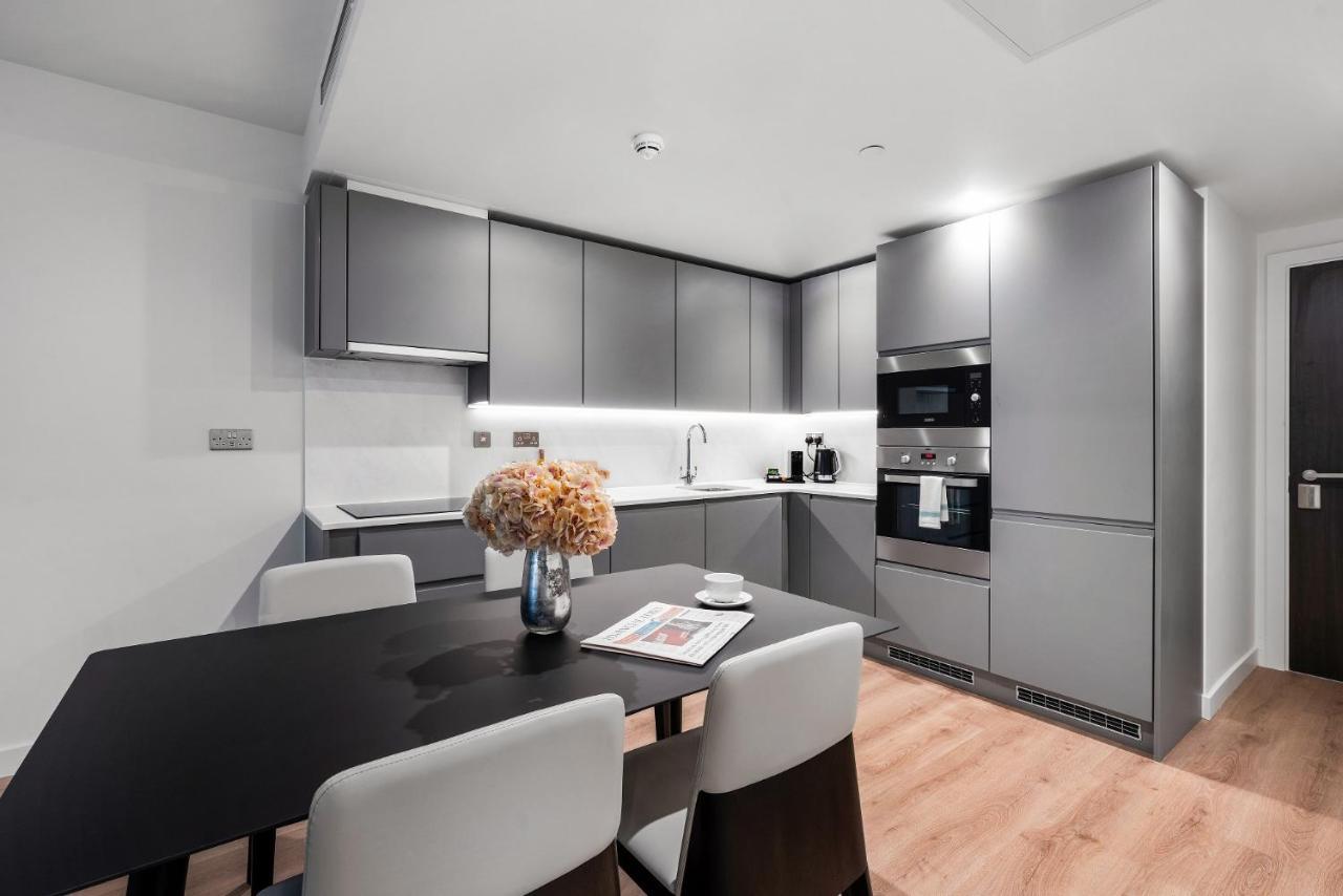 Citysuites 2 Aparthotel Manchester Exterior photo The photo shows a modern kitchen space. It features sleek, gray cabinetry with a minimalist design. There is a countertop with a sink, and appliances including an oven and a coffee maker. A dining table is positioned near the kitchen area, accompanie